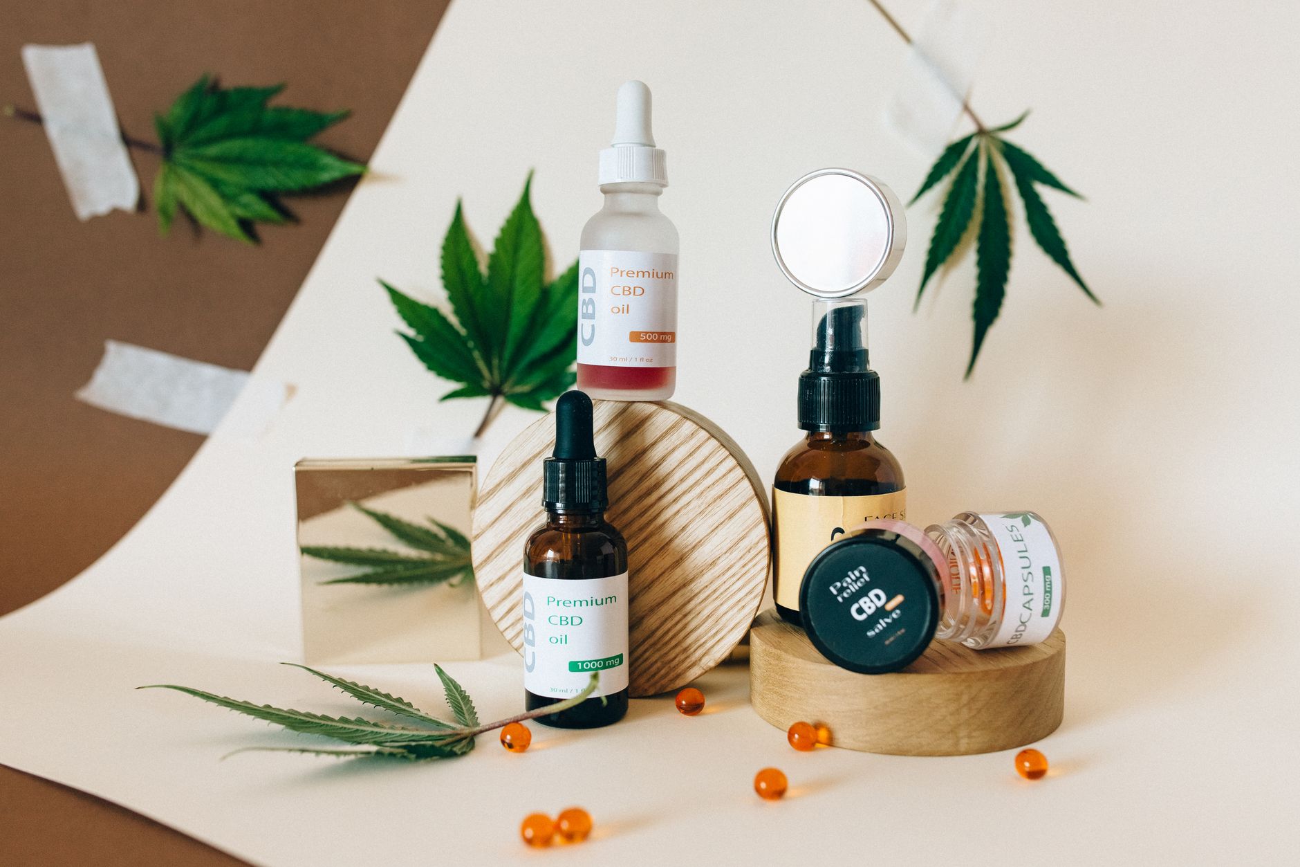 Uma coleção de produtos de óleo de CBD exibidos com folhas de cannabis em um fundo neutro.