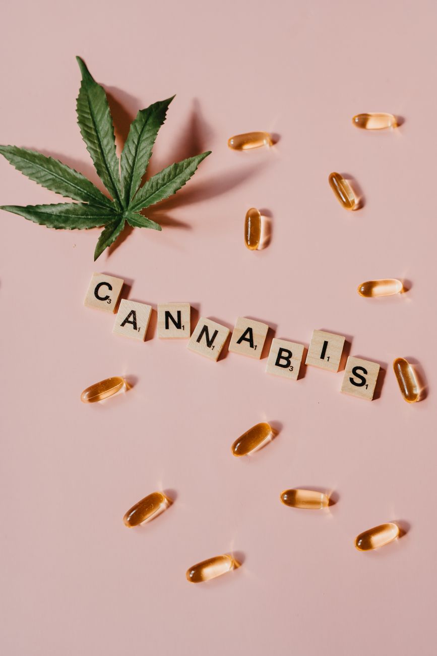 Vista superior de folhas de cannabis, óleo de CBD e acessórios de fumo sobre fundo de mármore.